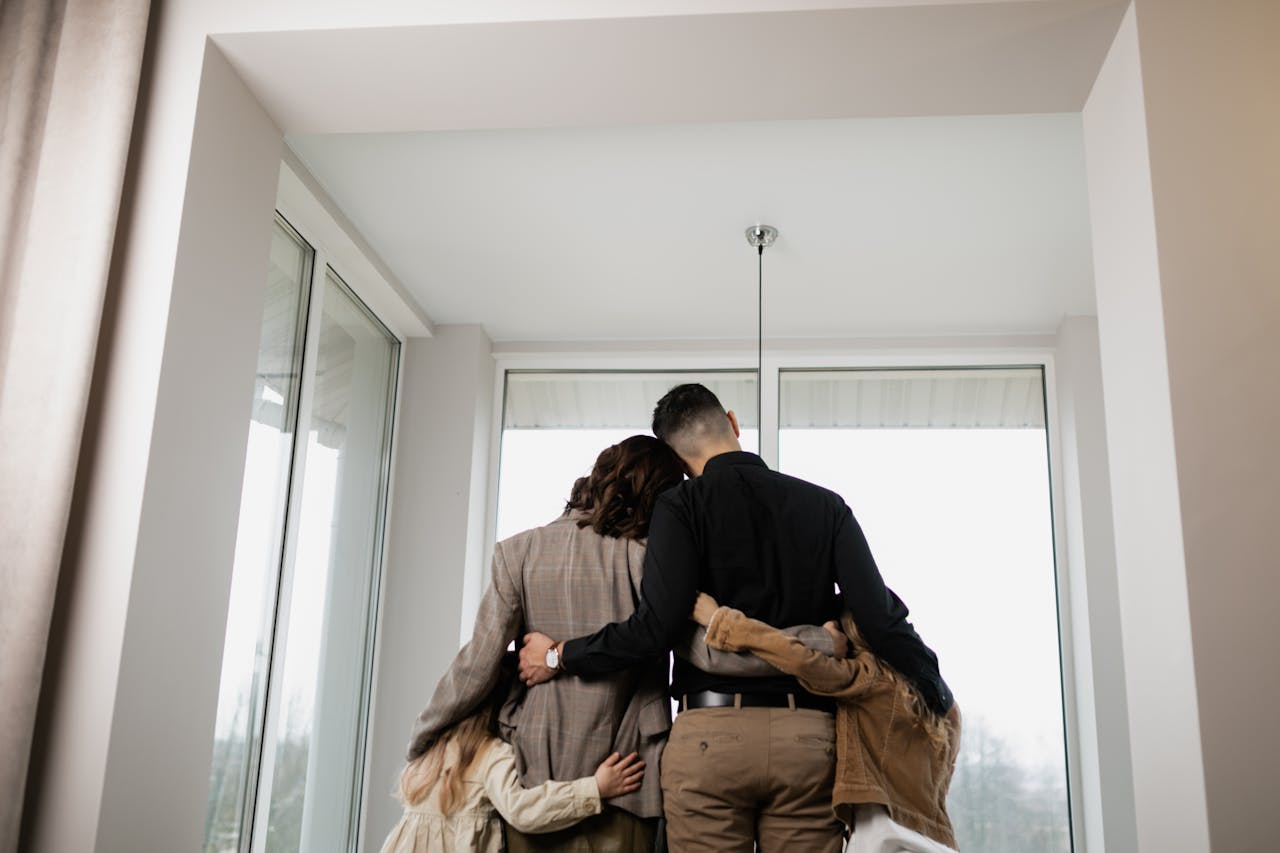 A family embraces warmly by a window, symbolizing love and togetherness indoors.