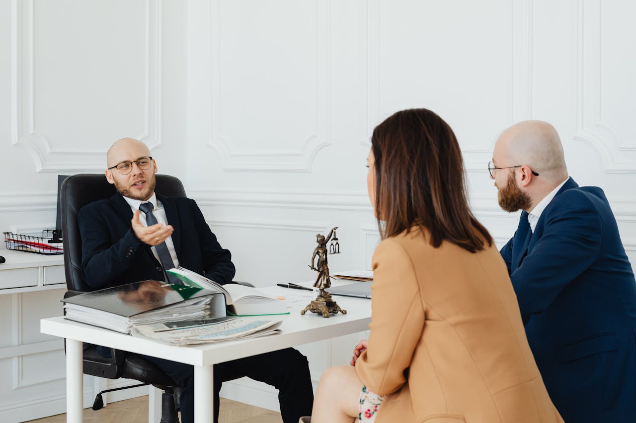 Three adults in a formal business meeting discussing legal matters in an office.